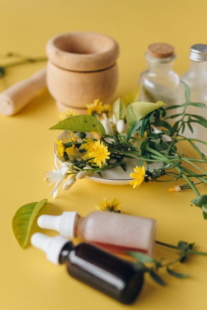 Still life of herbal remedies with yellow flowers on a vibrant yellow background.